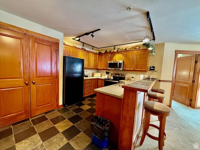 12080 E Big Cottonwood Rd Unit 214, Brighton, UT 84121 - kitchen with stainless steel appliances, a peninsula, brown cabinets, rail lighting, and a kitchen bar