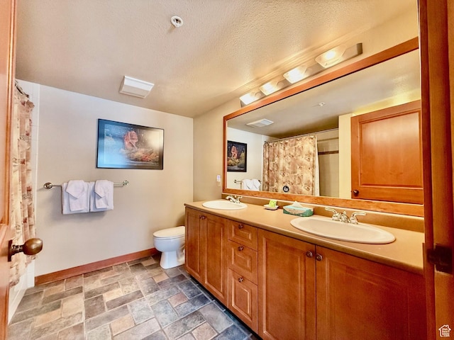 12080 E Big Cottonwood Rd Unit 214, Brighton, UT 84121 - bathroom with baseboards, double vanity, stone finish floors, toilet, and a textured ceiling
