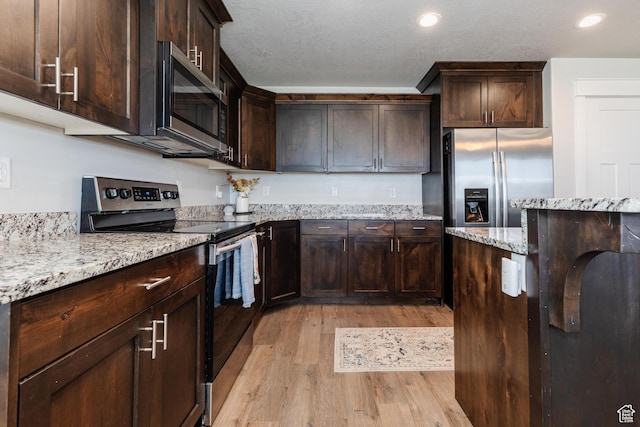 51 N 270 W, Hyrum, UT 84319 - kitchen featuring dark brown cabinets, appliances with stainless steel finishes, light wood-style floors, and light stone counters