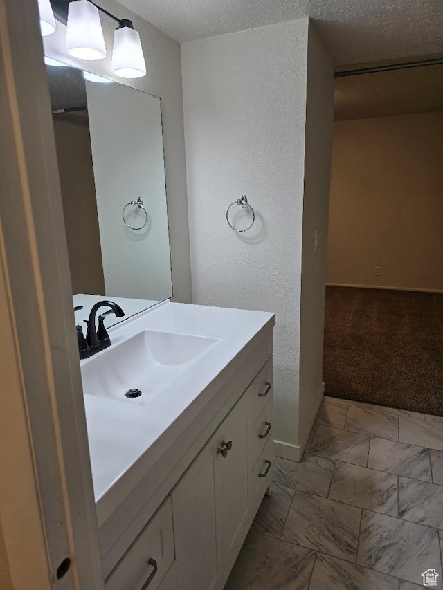 1039 E Quail Vista Ln Unit A, Millcreek, UT 84117 - bathroom with vanity, a textured wall, baseboards, a textured ceiling, and marble finish floor