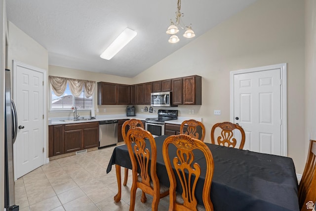 kitchen featuring dark brown cabinetry, light countertops, a sink, lofted ceiling, and stainless steel appliances