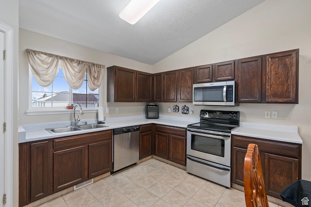 kitchen with a sink, light countertops, lofted ceiling, and stainless steel appliances