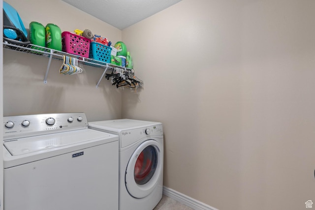 washroom with washer and dryer, laundry area, light tile patterned floors, and baseboards