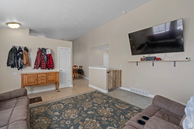 living area featuring a textured ceiling, light tile patterned floors, baseboards, and visible vents