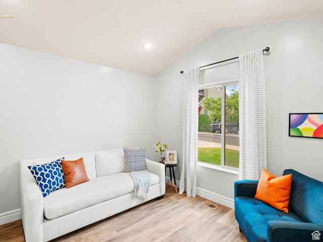 living area featuring baseboards, vaulted ceiling, and wood finished floors