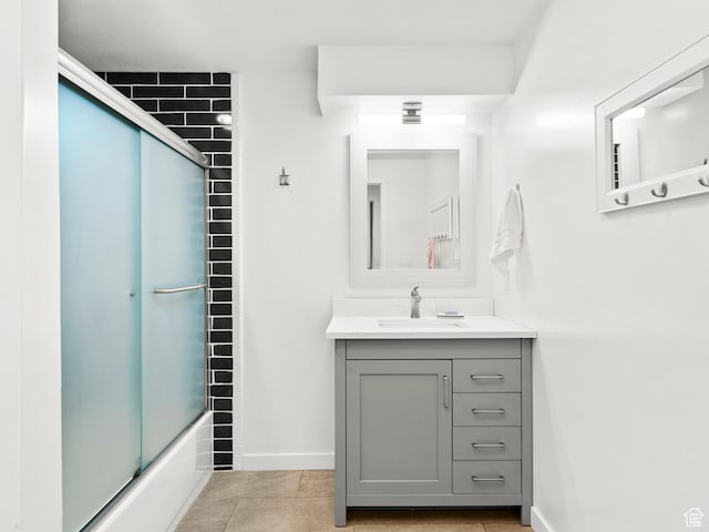 full bath featuring combined bath / shower with glass door, vanity, tile patterned floors, and baseboards