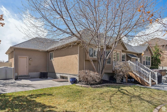 rear view of property featuring a patio area, entry steps, a yard, and stucco siding