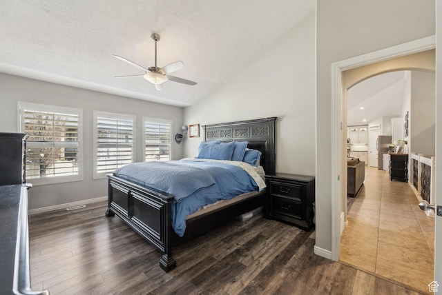 bedroom featuring baseboards, arched walkways, dark wood-style flooring, ceiling fan, and lofted ceiling