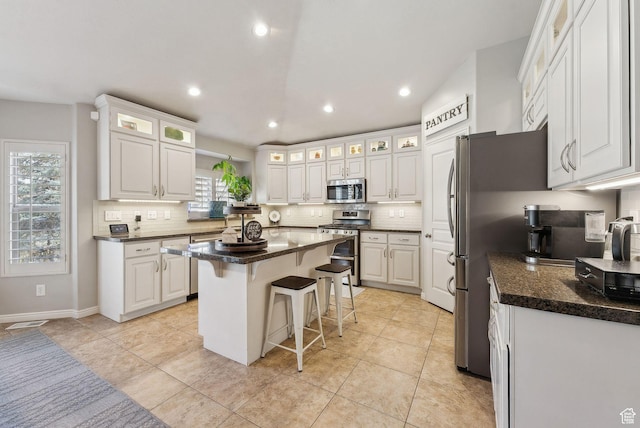 kitchen featuring appliances with stainless steel finishes, decorative backsplash, white cabinets, and a kitchen breakfast bar