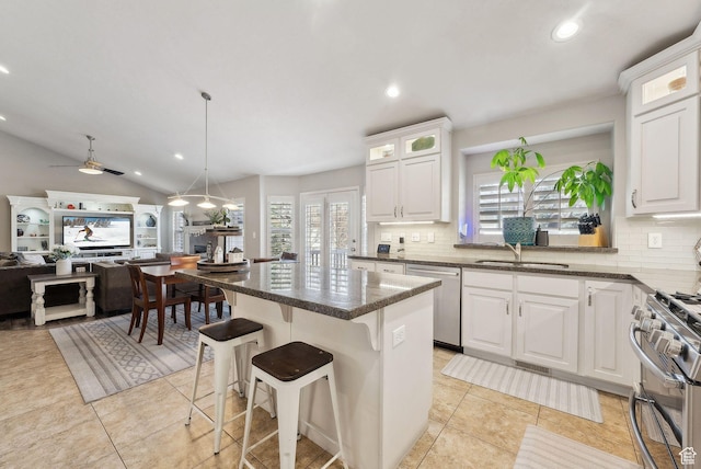 kitchen with glass insert cabinets, a center island, white cabinetry, appliances with stainless steel finishes, and a sink