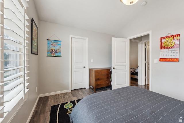 bedroom with baseboards, vaulted ceiling, and wood finished floors