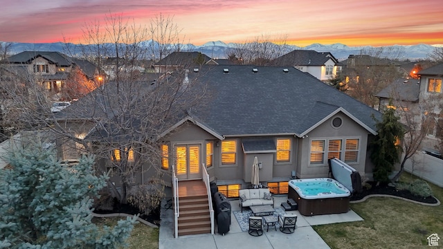 rear view of property with a mountain view, stucco siding, a patio, and roof with shingles
