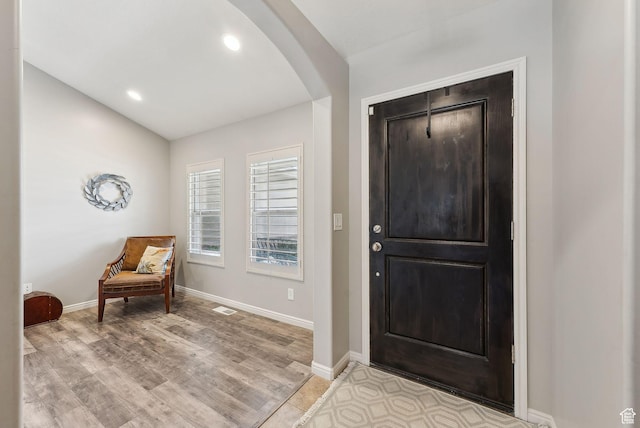 entrance foyer with arched walkways, light wood-type flooring, visible vents, recessed lighting, and baseboards