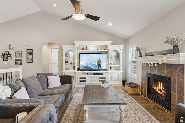 living area featuring arched walkways, ceiling fan, a fireplace, recessed lighting, and lofted ceiling