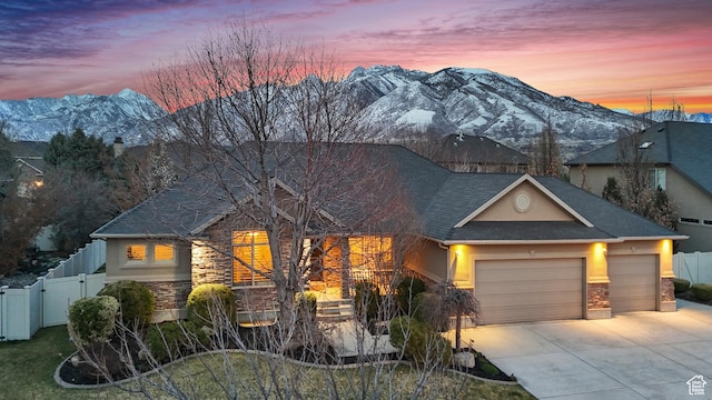 view of front of home with fence, stone siding, a mountain view, and a gate