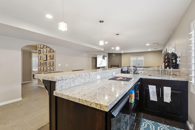 kitchen with light stone counters, a sink, baseboards, and recessed lighting