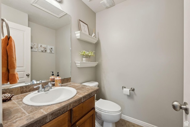 bathroom with toilet, vanity, and baseboards