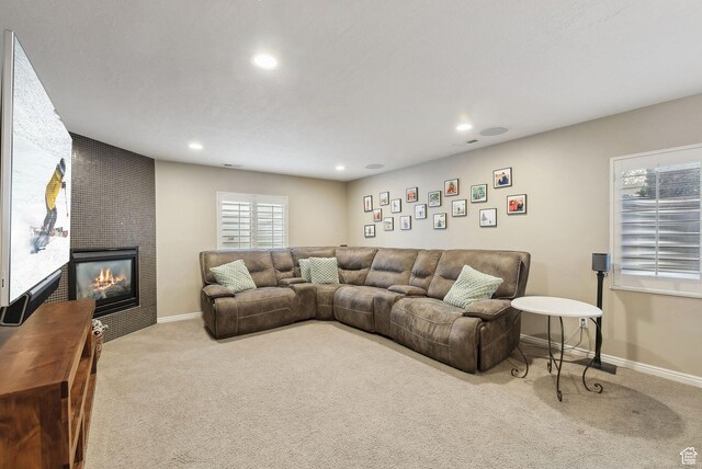 carpeted living area featuring a fireplace, baseboards, and recessed lighting