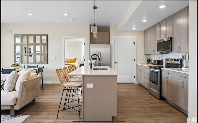 875 W Akoya Pearl St Unit 303, St George, UT 84790 - kitchen with appliances with stainless steel finishes, a sink, a breakfast bar area, gray cabinetry, and dark wood-style floors