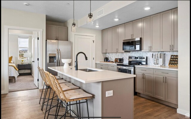 875 W Akoya Pearl St Unit 303, St George, UT 84790 - kitchen with a kitchen bar, stainless steel appliances, gray cabinetry, a center island with sink, and a sink