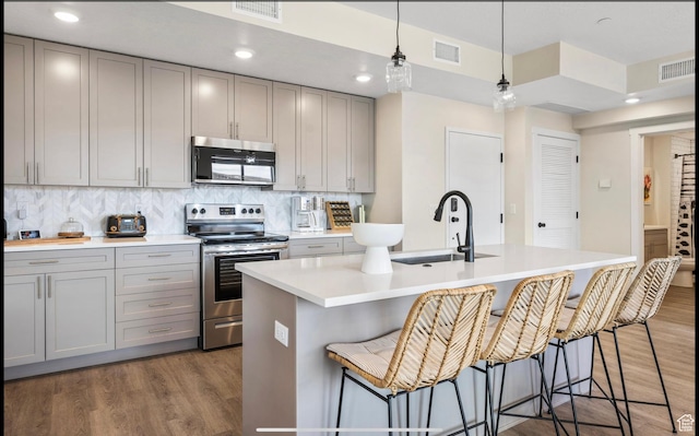 875 W Akoya Pearl St Unit 303, St George, UT 84790 - kitchen featuring decorative backsplash, visible vents, wood finished floors, appliances with stainless steel finishes, and gray cabinets
