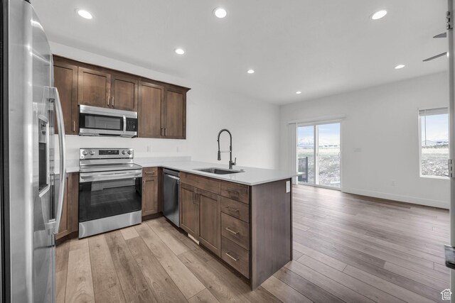 864 N Gleneagles Ct W, Tooele, UT 84074 - kitchen with light wood-style flooring, a sink, appliances with stainless steel finishes, and a peninsula