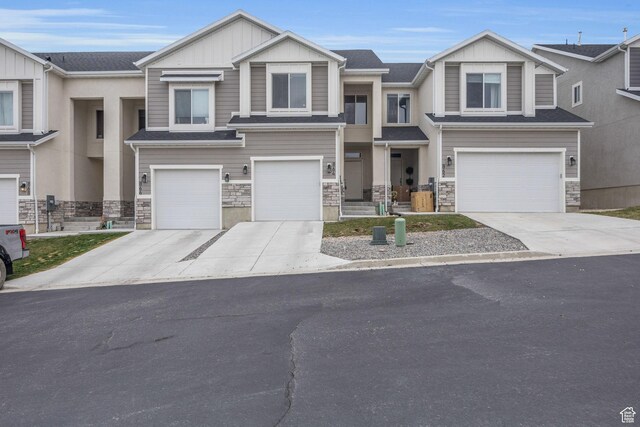 view of front of property featuring stone siding, board and batten siding, concrete driveway, and a garage
