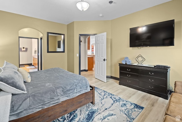 98 E Mt Peale Dr, Moab, UT 84532 - bedroom featuring arched walkways, baseboards, ensuite bathroom, and wood finished floors