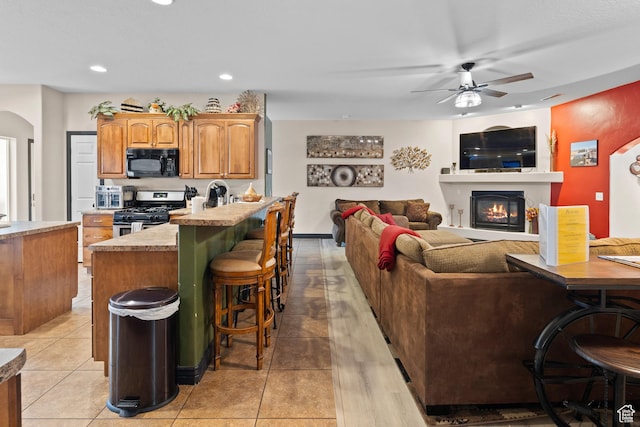 98 E Mt Peale Dr, Moab, UT 84532 - kitchen with stainless steel gas range oven, recessed lighting, ceiling fan, a glass covered fireplace, and black microwave