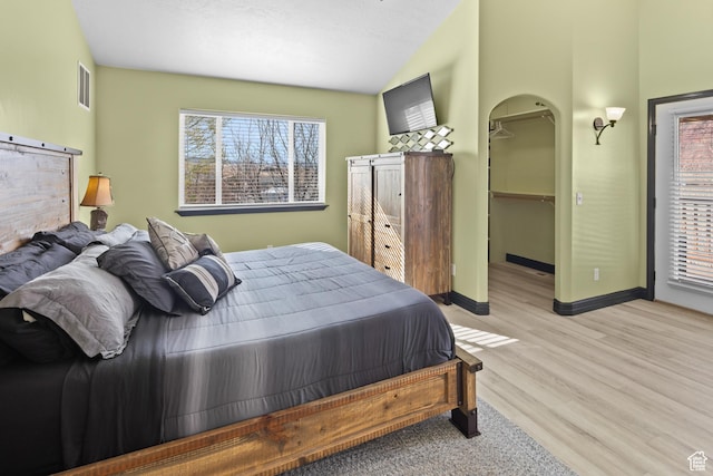 98 E Mt Peale Dr, Moab, UT 84532 - bedroom featuring light wood finished floors, lofted ceiling, baseboards, visible vents, and arched walkways