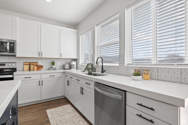 988 E Harrier St N, Eagle Mountain, UT 84005 - kitchen featuring appliances with stainless steel finishes, dark wood-type flooring, white cabinetry, a sink, and backsplash