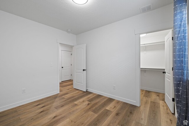 988 E Harrier St N, Eagle Mountain, UT 84005 - unfurnished bedroom with a closet, visible vents, baseboards, wood finished floors, and a spacious closet