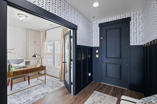 988 E Harrier St N, Eagle Mountain, UT 84005 - foyer entrance with a textured ceiling, visible vents, wallpapered walls, dark wood-type flooring, and wainscoting