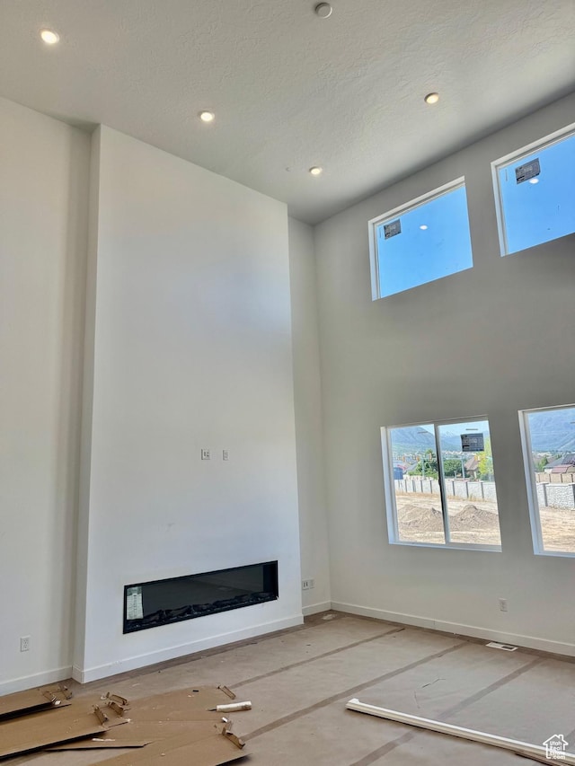 1002 E 250th St S Unit 17, Salem, UT 84653 - unfurnished living room with healthy amount of natural light, a glass covered fireplace, recessed lighting, and a high ceiling