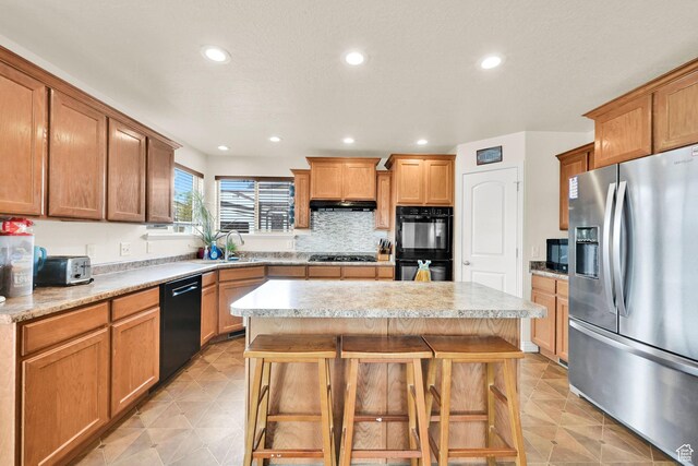 6007 W Jargon Way, Salt Lake City, UT 84118 - kitchen featuring light countertops, a center island, under cabinet range hood, a sink, and black appliances