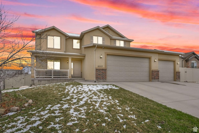 traditional home with concrete driveway, stucco siding, fence, an attached garage, and covered porch