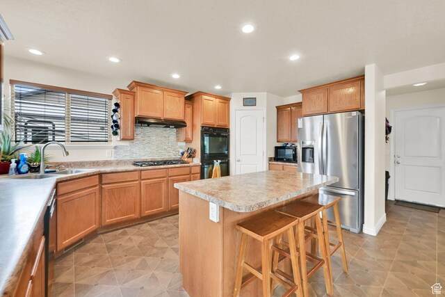 6007 W Jargon Way, Salt Lake City, UT 84118 - kitchen featuring light countertops, a sink, a kitchen bar, under cabinet range hood, and black appliances