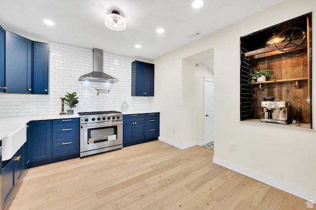 kitchen with visible vents, wall chimney exhaust hood, high end stainless steel range oven, and blue cabinets