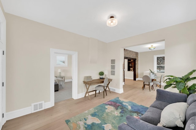 living area with baseboards, visible vents, and wood finished floors