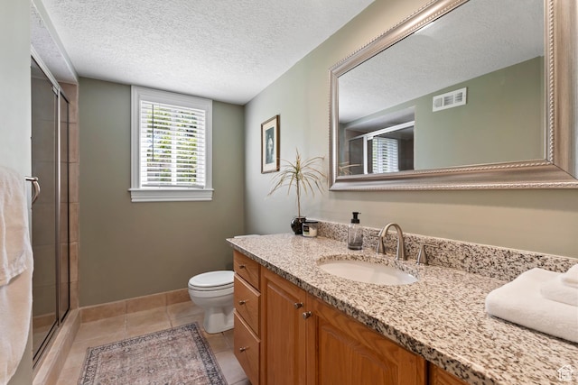 bathroom featuring a stall shower, vanity, toilet, baseboards, and a textured ceiling