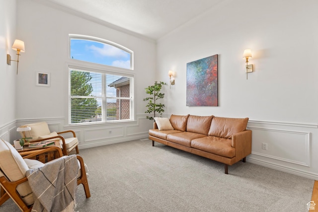 living area with plenty of natural light, carpet floors, a decorative wall, a wainscoted wall, and ornamental molding