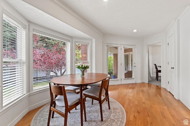dining space with plenty of natural light, light wood finished floors, crown molding, baseboards, and recessed lighting