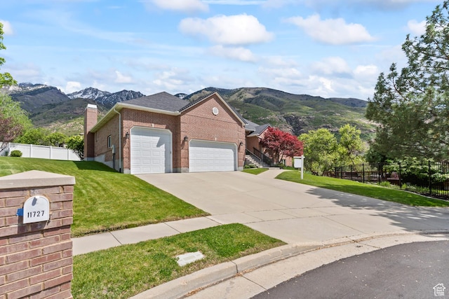 view of front of home with brick siding, an attached garage, a mountain view, concrete driveway, and a chimney