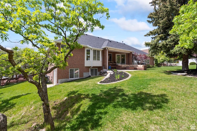 back of house with an outdoor living space, brick siding, and a lawn