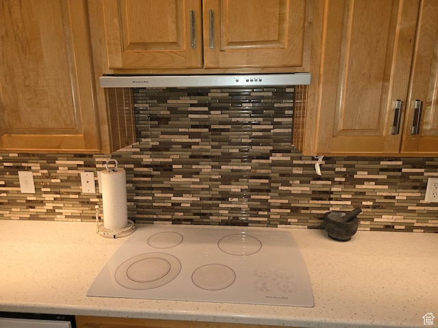 details featuring tasteful backsplash, white electric stovetop, and light countertops