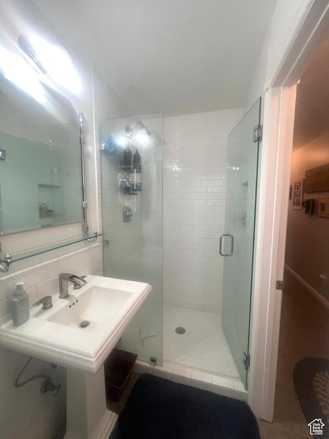 bathroom with a shower stall, a sink, and decorative backsplash