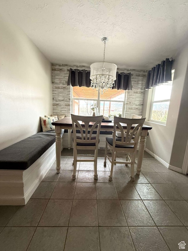 dining area featuring baseboards, a notable chandelier, and a textured ceiling