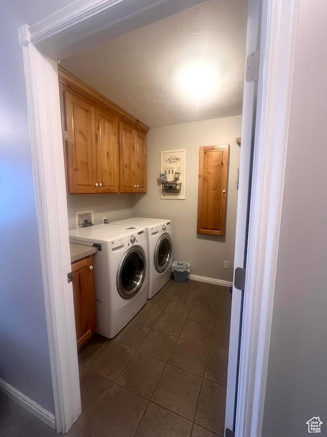 washroom with washer and clothes dryer, dark tile patterned floors, baseboards, and cabinet space