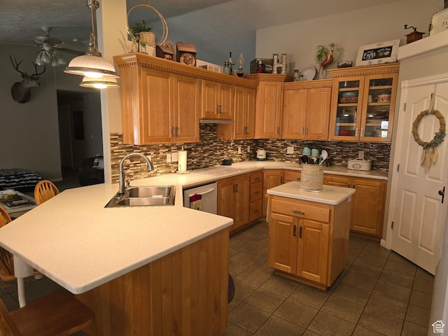kitchen featuring a kitchen breakfast bar, light countertops, ceiling fan, stainless steel dishwasher, and a sink