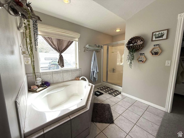 bathroom with baseboards, a shower stall, tile patterned flooring, and a garden tub